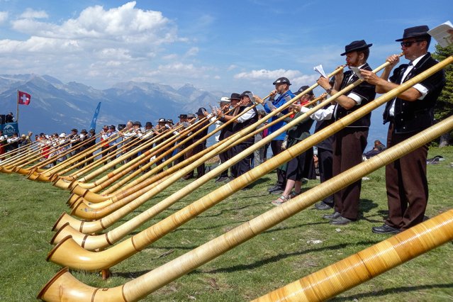 Approximately one hundred Alphorn players perform together on the final day of the 22th International Alphorn Festival on the mountain pasture of Tracouet, 2,200 metres up in the Swiss Alps above Nendaz on July 23, 2023. The wind instrument, which is a part of Swiss folklore and is used by mountain-dwellers in Switzerland, is made of wood with a cup-shaped mouthpiece. (Photo by Robin Millard/AFP Photo)