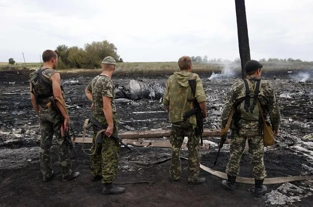 Armed pro-Russian separatists stand at the site of a Malaysia Airlines Boeing 777 plane crash near the settlement of Grabovo in the Donetsk region, July 17, 2014. The Malaysian airliner Flight MH-17 was brought down over eastern Ukraine on Thursday, killing all 295 people aboard and sharply raising the stakes in a conflict between Kiev and pro-Moscow rebels in which Russia and the West back opposing sides. (Photo by Maxim Zmeyev/Reuters)