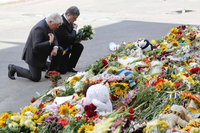 Ukraine's President Petro Poroshenko (R) and Dutch ambassador to Ukraine Kees Klompenhouwer commemorate victims of Malaysia Airlines Flight MH17 outside the Dutch embassy in Kiev July 21, 2014. The downing of the airliner with the loss of nearly 300 lives has sharply escalated the crisis in Ukraine, and may mark a pivotal moment in international efforts to resolve a situation in which separatists in the Russian-speaking east have been fighting government forces since protesters in Kiev forced out a pro-Moscow president and Russia annexed Crimea. (Photo by Valentyn Ogirenko/Reuters)
