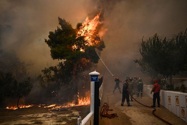 A firefighter sprays water on flames during a wildfire in Chasia in the outskirts of Athens on August 22, 2023. Greece's fire brigade on August 22, 2023 ordered the evacuation of a district on Athens' northwestern flank as firefighters battled a steadily growing wave of wildfires around the country, the second in a month. Tens of thousands of people have been urged to leave the district of Ano Liosia, while at the neighbouring community of Fyli an AFP journalist saw homes on fire. (Photo by Angelos Tzortzinis/AFP Photo)