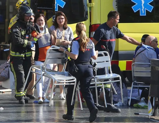 Injured people are treated in Barcelona, Spain, Thursday, August 17, 2017 after a white van jumped the sidewalk in the historic Las Ramblas district, crashing into a summer crowd of residents and tourists and injuring several people, police said. (Photo by Oriol Duran/AP Photo)