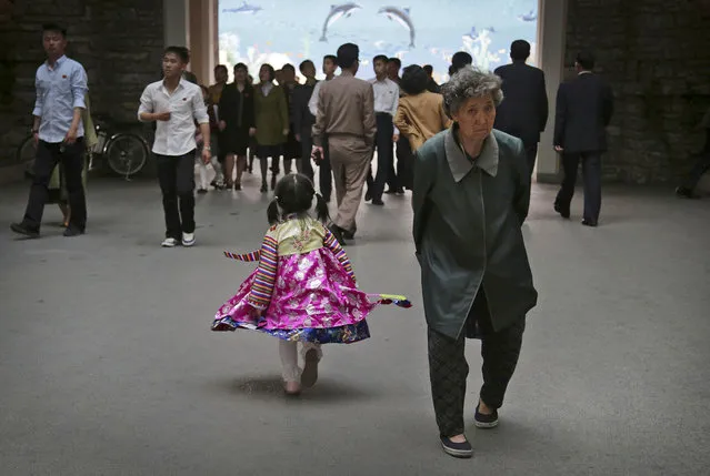 In this April 16, 2017, file photo, a young girl in traditional dress walks past an elderly woman at the Central Zoo, in Pyongyang, North Korea. A generational divide is quietly growing in North Korea. For generations, propaganda about the Kim family was all that most North Koreans knew, a mythology of powerful but tender-hearted rulers who protect their people against a hostile world. Many older North Koreans feel that emotional tug. (Photo by Wong Maye-E/AP Photo)