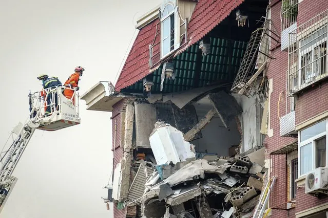A fireman looks into the partially collapsed section of a building in China's Tianjin Municipality Tuesday, July 19, 2022. A gas explosion left some missing and others injured. (Photo by Chinatopix Via AP Photo)