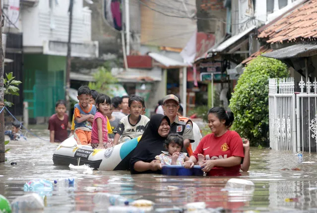 Residents walk in a flooded street in Jakarta, Indonesia, 25 February 2020. According the National Disaster Management Authority (BNPB), heavy rains triggered widespread flooding in Jakarta, with floodwaters reaching a depth of more than 150cm in some areas. (Photo by Adi Weda/EPA/EFE)