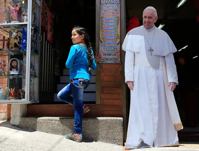 A girl stands next to a life-size image of Pope Francis in Bogota, ahead of his upcoming visit, on August 13, 2017. Pope Francis will make a special four-day visit to Colombia, from September 6-11, to add his weight to the process of reconciliation between the government and the FARC. (Photo by John Vizcaino/AFP Photo)