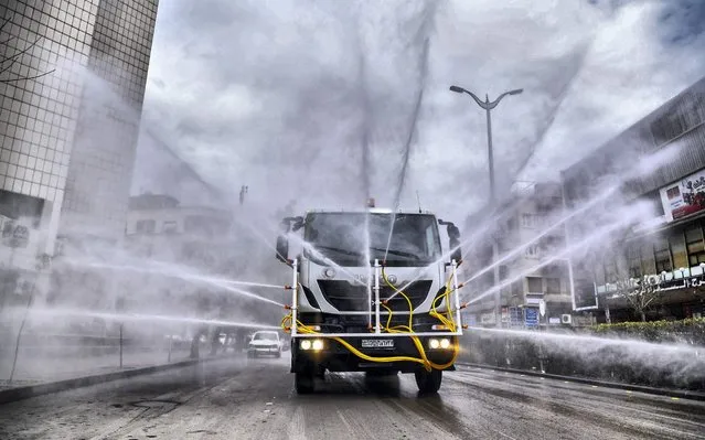 A handout picture released by the official Syrian Arab News Agency (SANA) on March 20, 2020 shows Syrian Red Crescent vehicles spraying disinfectant along a street in the capital Damascus, as part of measures against the spread of COVID-19 coronavirus disease. (Photo by SANA/AFP Photo)