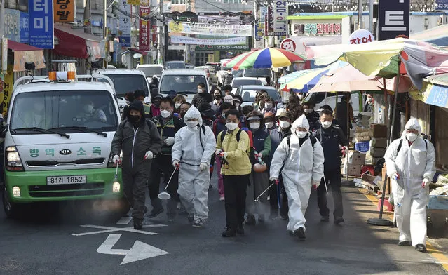 Residents spray disinfectant as a precaution against a new coronavirus at a traditional market in Suwon, South Korea, Wednesday, March 25, 2020. (Photo by Kim Jong-taek/Newsis via AP Photo)