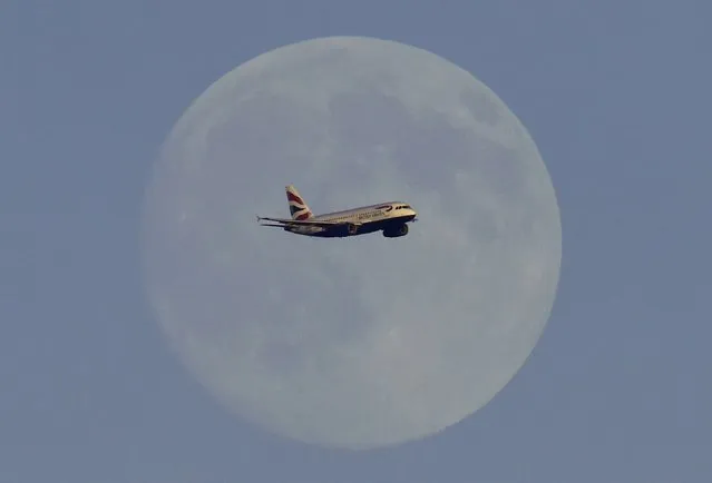 A British Airways passenger aircraft passes in front of the moon as it makes it's landing approach towards Heathrow Airport in west London in this photograph taken on July 18, 2016. (Photo by Toby Melville/Reuters)