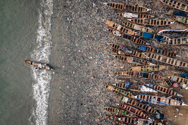 This aerial view shows a boat arriving on the polluted shore of the James Town Fishing Harbour in Accra, Ghana on December 12, 2024. (Photo by Olympia de Maismont/AFP Photo)