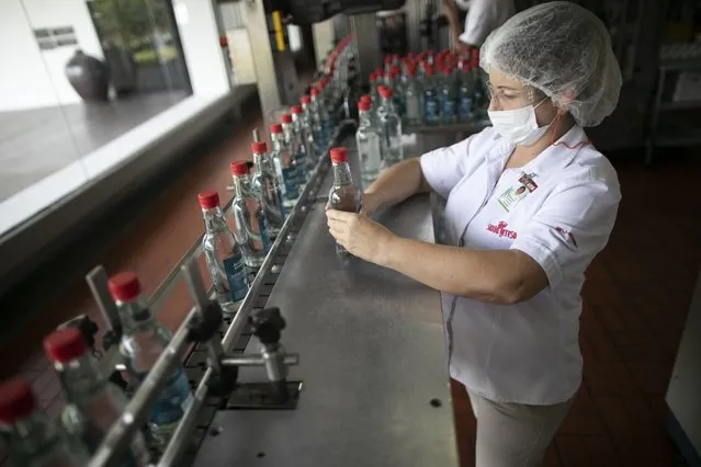 A worker inspects bottles of antiseptic alcohol at the Santa Teresa rum factory in La Victoria, Aragua state, Venezuela, Wednesday, April 1, 2020. Venezuela's premier rum distillery and one of Venezuela's few private businesses says that most of its production will be for antiseptic alcohol, in an effort to help contain the spread of the new coronavirus. (Photo by Ariana Cubillos/AP Photo)