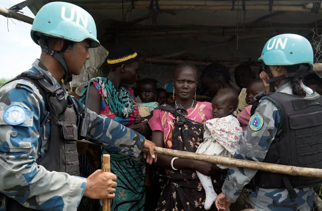 United Nations peacekeepers control South Sudanese women and children before the distribution of emergency food supplies at the United Nations protection of civilians (POC) site 3 hosting about 30,000 people displaced during the recent fighting in Juba, South Sudan, July 25, 2016. (Photo by Adriane Ohanesian/Reuters)