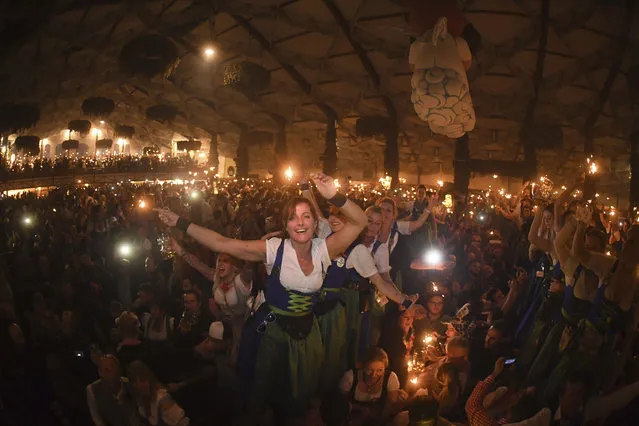 In this October 3, 2017 photo waitresses celebrate after closing of a tent on the last day of the Oktoberfest beer festival in Munich, southern Germany. (Photo by Felix Hoerhager/DPA via AP Photo)