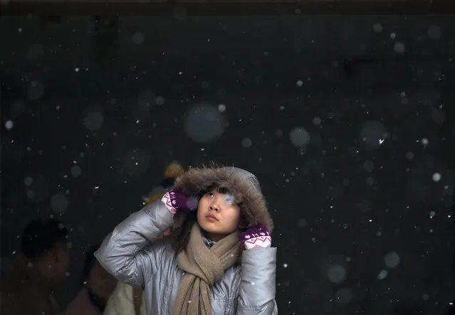 A Chinese woman looks up as she exits from an underground tunnel in a snowfall in Beijing Wednesday, December 12, 2012. (Photo by Andy Wong/AP Photo)