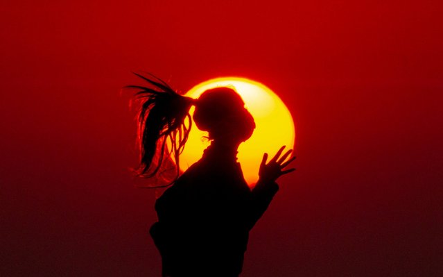 A girl wears a mask to help protect herself from the new coronavirus jogs as the sun sets over the Mediterranean Sea coastline, in Beirut, Lebanon, Tuesday, April 14, 2020. (Photo by Hassan Ammar/AP Photo)