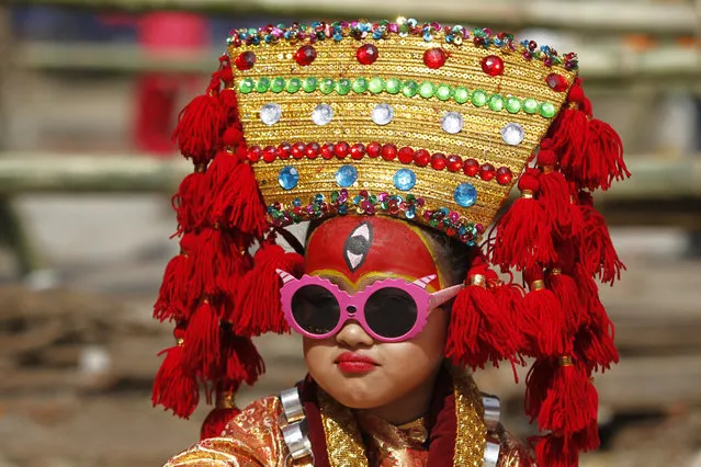 A Nepalese girl dressed as living goddess Kumari waits for Kumari Puja at Hanuman Dhoka, Basantapur Durbar Square in Kathmandu, Nepal, Monday, September 4, 2017. Girls under the age of nine gathered for the Kumari puja, a tradition of worshiping young prepubescent girls as manifestations of the divine female energy. The ritual holds a strong religious significance in the Newar community that seeks divine blessings to save small girls from diseases and bad luck in the years to come. (Photo by Niranjan Shrestha/AP Photo)