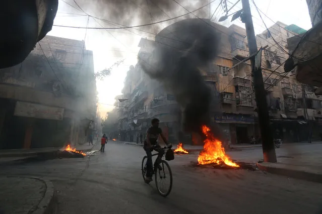 A man rides a bicycle past burning tyres, which activists said are used to create smoke cover from warplanes, in Aleppo, Syria  August 1, 2016. (Photo by Abdalrhman Ismail/Reuters)