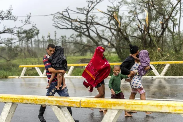 A family walks in the rain after Hurricane Ian hit Pinar del Rio, Cuba, Tuesday, September 27, 2022. Ian made landfall at 4:30 a.m. EDT Tuesday in Cuba’s Pinar del Rio province, where officials set up shelters, evacuated people, rushed in emergency personnel and took steps to protect crops in the nation’s main tobacco-growing region. (Photo by Ramon Espinosa/AP Photo)