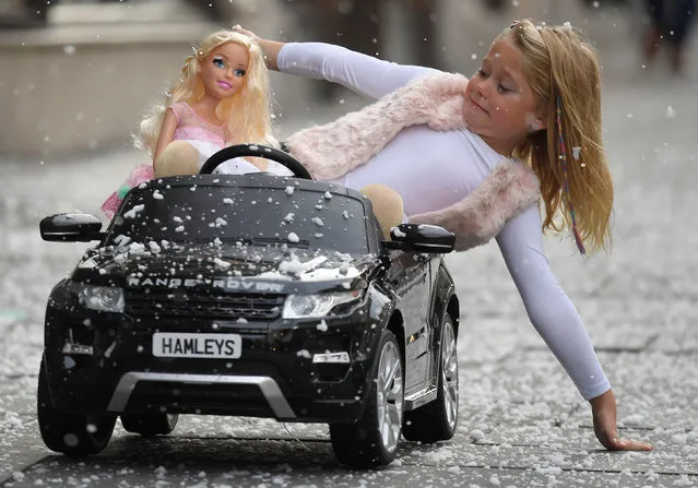 Six year old Lillie reacts as she poses with a children's Range Rover Evoque ride-on car and a Barbie fashion doll, which form part of the selection of predicted top sellers this Christmas at the Hamleys toy store in London, Britain, October 12, 2017. (Photo by Toby Melville/Reuters)