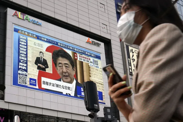 A public screen shows Japanese Prime Minister Shinzo Abe speaking at a press conference Monday, May 25, 2020, in Tokyo. Abe lifted a coronavirus state of emergency in Tokyo and four other remaining areas on Monday, ending the restrictions nationwide as businesses begin to reopen. (Photo by Eugene Hoshiko/AP Photo)