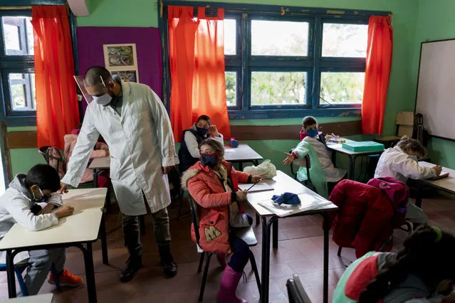 Wearing face masks amid the new coronavirus pandemic, a teacher leads his class on the first day back to a rural school near Empalme Olmos, Uruguay, Monday, June 1, 2020, as Uruguay’s total lockdown begins to ease. (Photo by Matilde Campodonico/AP Photo)