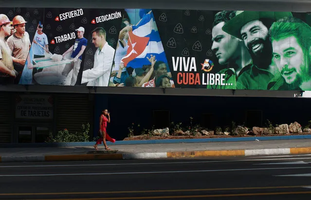 A woman passes a state outdoor sign with images of late Cuban revolutionaries heroes Ernesto “Che” Guevara (R), Camilo Cienfuegos (2nd-R) and cofounder of the first Communist Party of Cuba, Julio Antonio Mella (3rd-R), with a message reading: “Long Live Free Cuba” in Havana, Cuba, May 18, 2016. (Photo by Alexandre Meneghini/Reuters)