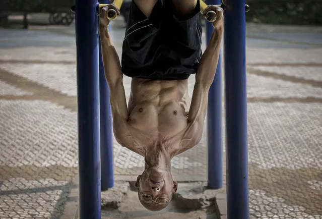 A Chinese holds himself upside down as he exercises on bars at a park September 10, 2014 in Beijing, China. (Photo by Kevin Frayer/Getty Images)