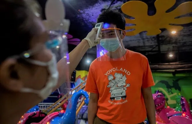 An employee measures the temperature of another in Yoyo Land, an indoor amusement center in Bangkok, Thailand, Tuesday, June 16, 2020. Daily life in the capital resumes to normal as the government continues to ease restrictions related to running business and activities that were imposed weeks ago to combat the spread of COVID-19. Thailand reported no local transmissions of the coronavirus in the past 3 weeks. (Photo by Gemunu Amarasinghe/AP Photo)