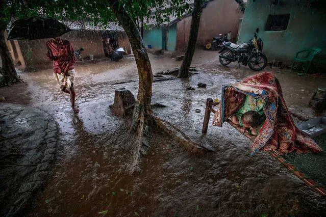 Save Me: Sourav Das, India. 4th place, Water category. At one point, a few children were playing and suddenly the sky collapsed and the rain came pouring down. There was no shelter in the area, until their father ran to save them from the rain. (Photo by Sourav Das/2020 Hamdan International Photography Award)
