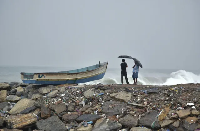 Two men hold umbrellas to protect themselves from the rain as they stand next to a fishing boat on the Arabian Sea coast in Thiruvananthapuram, Kerala state, India, Friday, December1, 2017. Dozens of fishermen were rescued Friday from the sea which is very rough under the influence of Cyclone Ockhi. (Photo by AP Photo/Stringer)