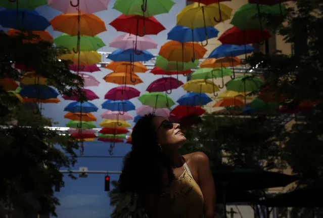 Julia Pena, 19, of Miami, observes an art installation called Umbrella Sky on Monday, July 16, 2018, in Coral Gables, Fla. (Photo by Brynn Anderson/AP Photo)