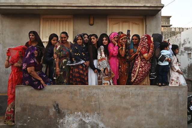 Hindu women watch the procession as they celebrate Hindu festival of Holi in Tharparkar district of the desert town of Mithi, south-eastern Pakistan, on March 13, 2025. In a desert town in Pakistan, Hindus prepare meals for fasting Muslims, who in turn gather to welcome a Holi procession, a rare moment of religious solidarity in the Islamic nation. (Photo by Asif Hassan/AFP Photo)