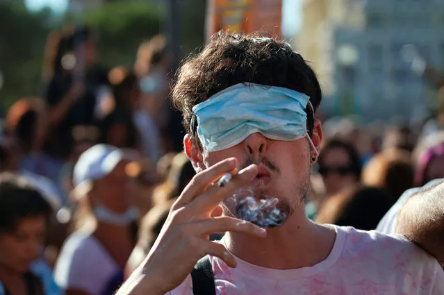 A man smokes a cigarette with his eyes covered by a face mask as he takes part in a protest against the use of protective masks during the coronavirus disease (COVID-19) pandemic, in Madrid, Spain on August 16, 2020. (Photo by Juan Medina/Reuters)