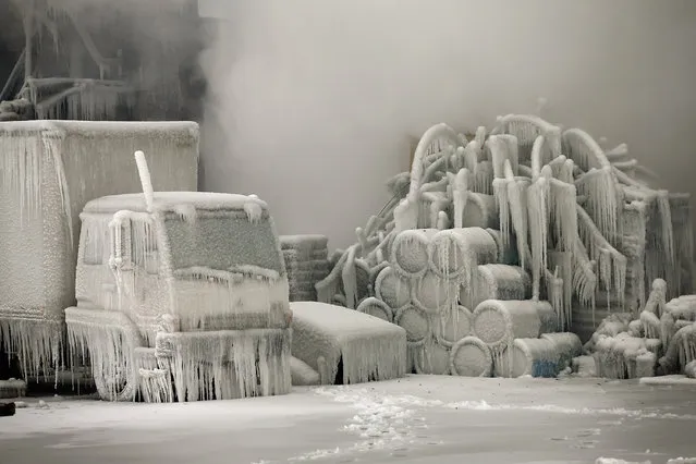 A truck is covered in ice as firefighters help to extinguish a massive blaze at a vacant warehouse on January 23, 2013 in Chicago, Illinois. More than 200 firefighters battled a five-alarm fire as temperatures were in the single digits. (Photo by Scott Olson)