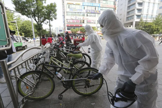 Workers and volunteers disinfect as a precaution against the coronavirus on a street in Goyang, South Korea, Tuesday, August 25, 2020. South Korea is closing schools and switching back to remote learning in the greater capital area as the country counted its 12th straight day of triple-digit daily increases in coronavirus cases. (Photo by Ahn Young-joon/AP Photo)