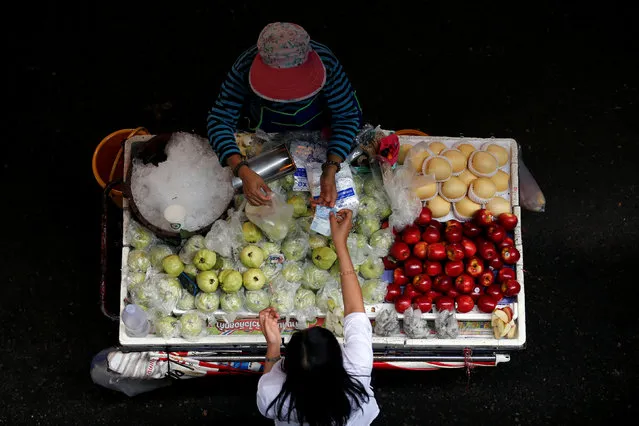 A street vendor sells guava and other fruits to a customer in Bangkok, Thailand September 2, 2016. (Photo by Chaiwat Subprasom/Reuters)