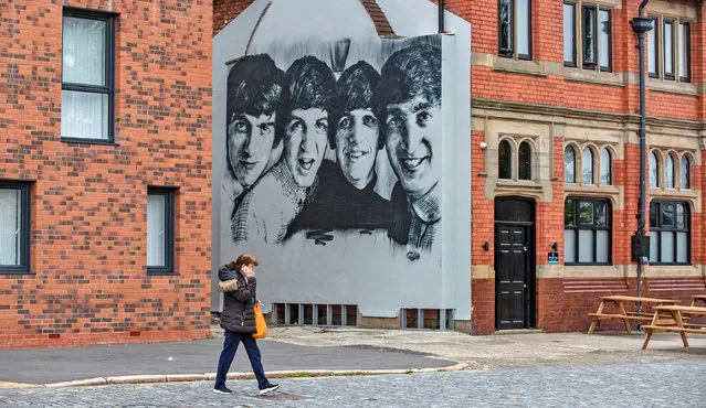 A woman walks past a new Beatles mural on the gable end of The Pheonix pub in Kirkdale, Liverpool on  on September 6, 2020. (Photo by Peter Byrne/PA Images via Getty Images)