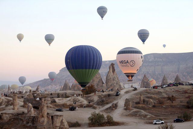 Hot air balloons glide over Nevsehir, Turkiye on November 28, 2022. Hot air balloon tours providing a bird's eye view of the region, are organized every morning for tourists in Cappadocia, which is on the UNESCO World Cultural Heritage List as one of the important tourism centers with its natural, historical and cultural heritage. Between January and November, 629 thousand 283 tourists visited Cappadocia this year. (Photo by Behcet Alkan/Anadolu Agency via Getty Images)