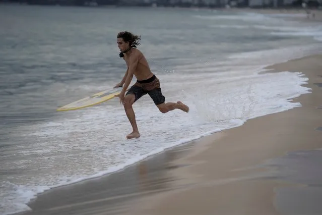 Leo Freitas runs to take a wave at Ipanema beach in Rio de Janeiro, Brazil, Monday, June 8, 2020. For the 18-year-old skimboard athlete, people need to take appropriate precautions when they go out, amid the new coronavirus pandemic, after the authorities have started to reopen gradually some businesses and easing some protective measures. (Photo by Leo Correa/AP Photo)