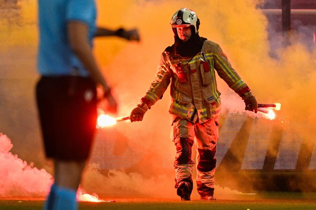 A fire fighter takes a firework at the start of a soccer game between Belgian club Royale Union Saint Gilloise and Turkish club Fenerbahce, on Thursday 07 March 2024 in Brussels, the first leg of the 1/8 finals of the UEFA Conference League competition. (Photo by Rex Features/Shutterstock)
