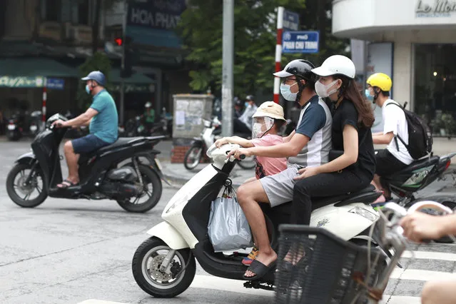 People wearing face masks ride motorcycles in Hanoi, Vietnam, Monday, August 3, 2020. Vietnam has tightened travel and social restrictions after the country's death toll of COVID-19 to six. (Photo by Hau Dinh/AP Photo)