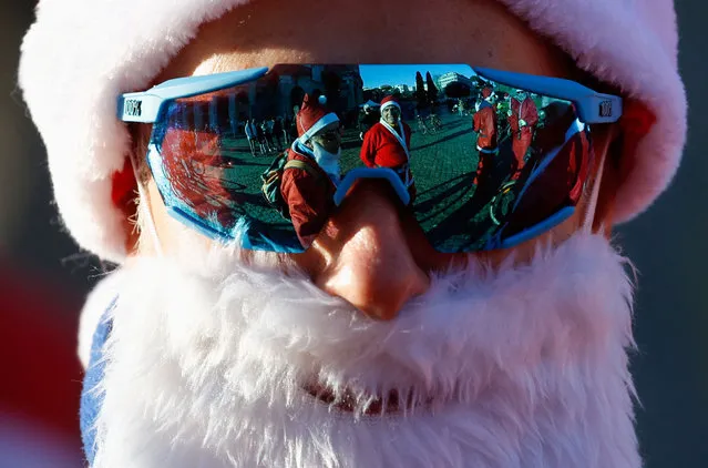 People dressed up in Father Christmas costumes are reflected in sunglasses on the day of the ride through the city centre to raise money for children's charities in Rome, Italy on December 18, 2022. (Photo by Remo Casilli/Reuters)