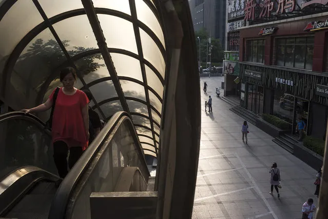 People ride up an outdoor escalator in the Chaoyang district of Beijing on May 24, 2016. China's capital city has swelled to over 20 million. (Photo by Michael Robinson Chavez/The Washington Post)