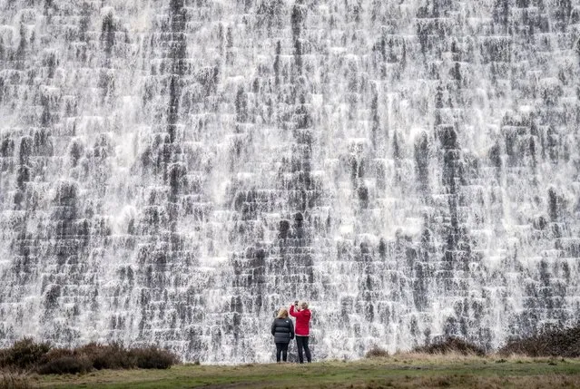 People look on as water pours down the front of Derwent Dam in Derbyshire on Monday, January 9, 2023, ahead of a Met Office yellow weather warning for rain, for parts of the UK on Tuesday. (Photo by Danny Lawson/PA Images via Getty Images)