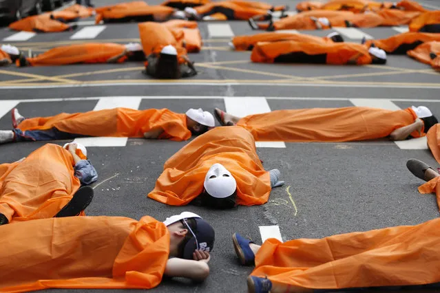 Taiwanese workers wearing white masks lie down on a street during a protest outside a goverment office in Taipei, Taiwan, 26 October 2015. Protesters said that the government allegedly revised its hiring policy in 2012 and has laid off around 15,000 contracted and temporary employees. They also calls on candidates in the up-coming election to take care of workers interests. (Photo by Ritchie B. Tongo/EPA)