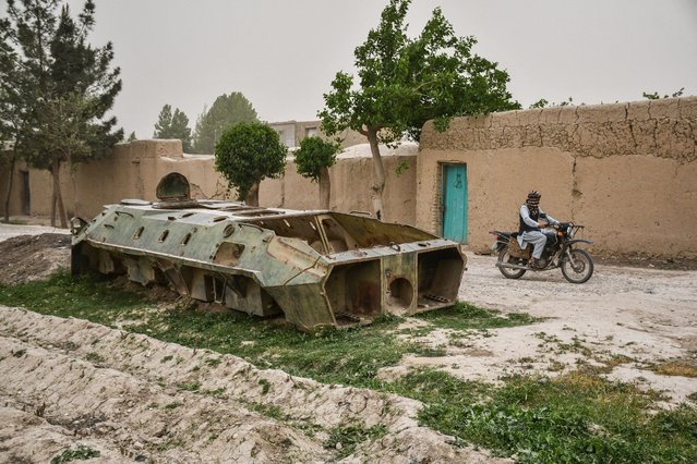 An Afghan motorcyclist rides past the remains of a Soviet-era military tank in Balkh province on April 17, 2025. (Photo by Atif Aryan/AFP Photo)