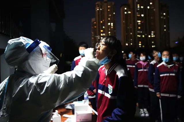This photo taken on October 12, 2020 shows a health worker taking a swab from a middle school student to be tested for the COVID-19 coronavirus, as part of a mass testing program following a new coronavirus outbreak in Qingdao, in China's eastern Shandong province. (Photo by AFP Photo/China Stringer Network)