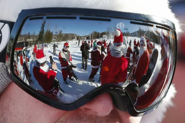 Skiers and snowboarders dressed as Santa Claus are reflected in a skier's goggles before participating in a charity run down a slope at Sunday River Ski Resort in Newry, Maine December 7, 2014. (Photo by Brian Snyder/Reuters)