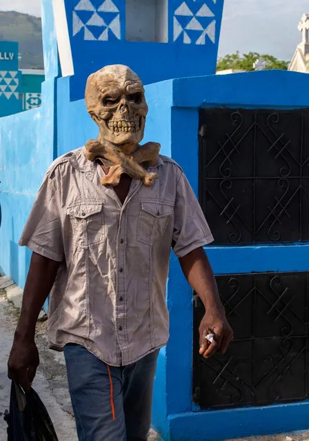 A Voodoo believer walks while wearing a plastic mask at the national cemetery during ceremonies honoring the Haitian Voodoo spirit of Baron Samdi and Gede on the Day of the Dead, in Port-au-Prince, Haiti, Sunday, November 1, 2020. (Photo by Dieu Nalio Chery/AP Photo)