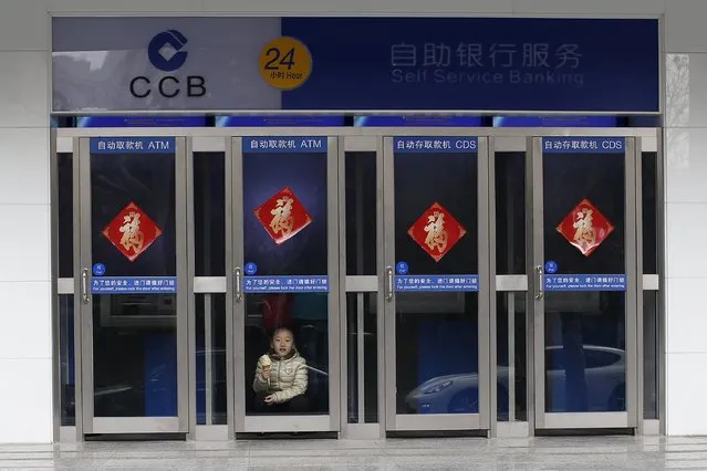 A child eats an ice cream at the ATM machines of a branch of China Construction Bank (CCB) in downtown Shanghai in this January 30, 2015 file photo. (Photo by Aly Song/Reuters)