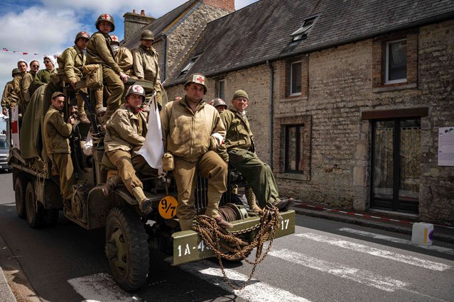 Enthusiasts wearing replica WWII military attire ride atop a WWII-era military truck in Saint-Come-du-Mont, northwestern France, on June 4, 2024, as part of the “D-Day” commemorations marking the 80th anniversary of the World War II Allied landings in Normandy. The D-Day ceremonies on June 6 this year mark the 80th anniversary since the launch of “Operation Overlord”, a vast military operation by Allied forces in Normandy, which turned the tide of World War II, eventually leading to the liberation of occupied France and the end of the war against Nazi Germany. (Photo by Miguel Medina/AFP Photo)